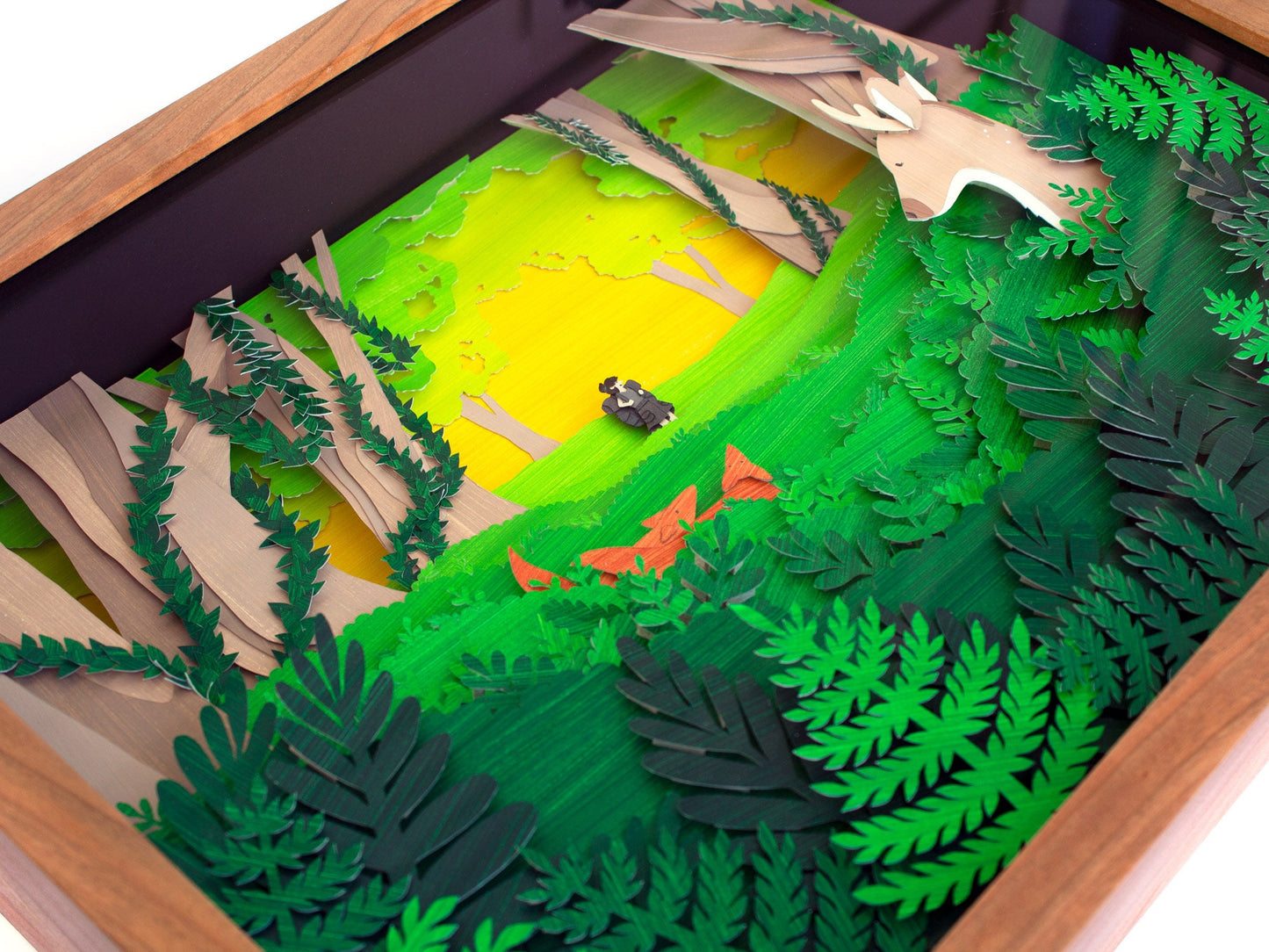 Framed cut paper illustration of cute forrest scene with deer, fox, and hiker.