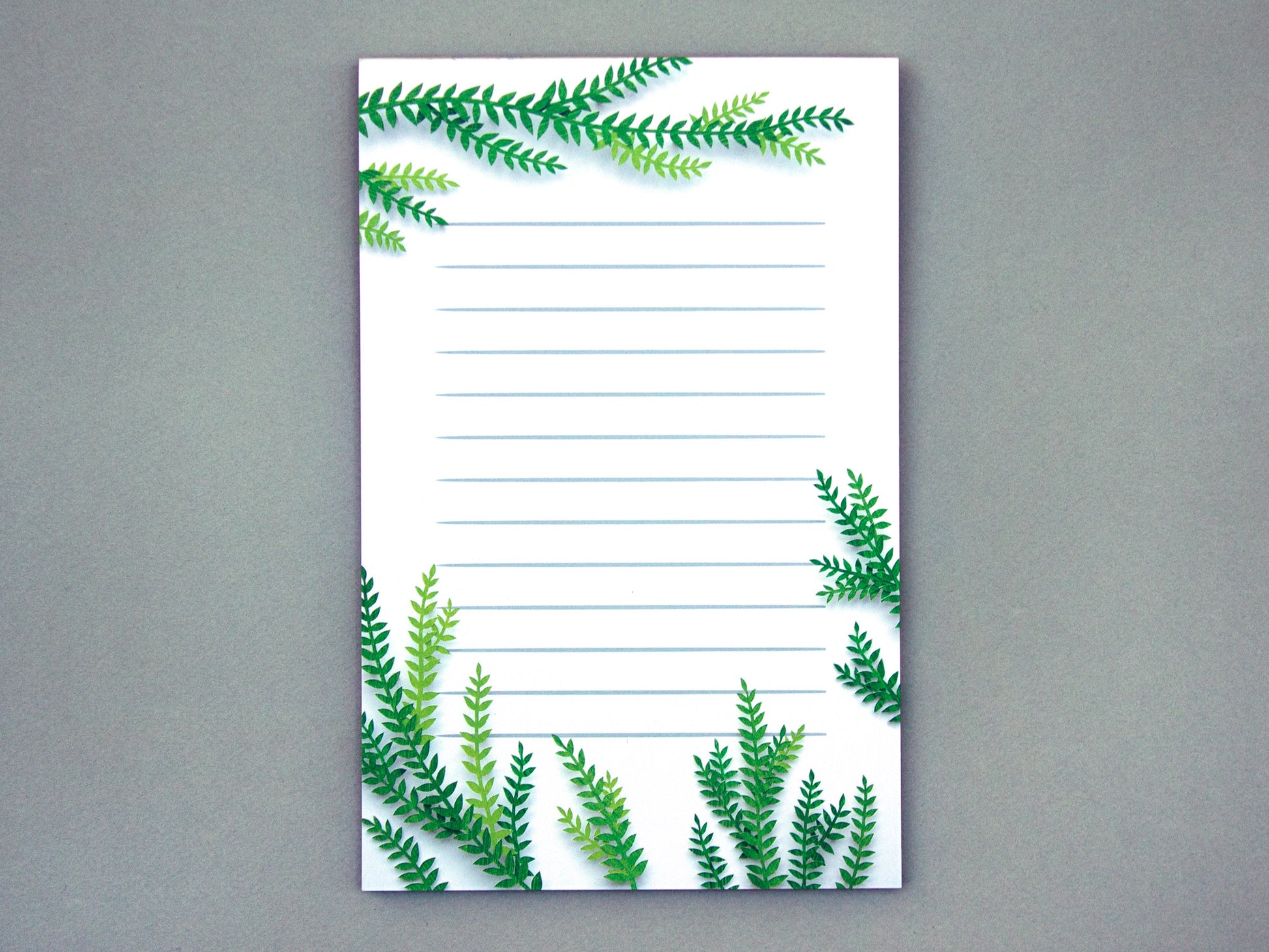 Notepad with cut paper illustration of tree branches at the top and bottom.