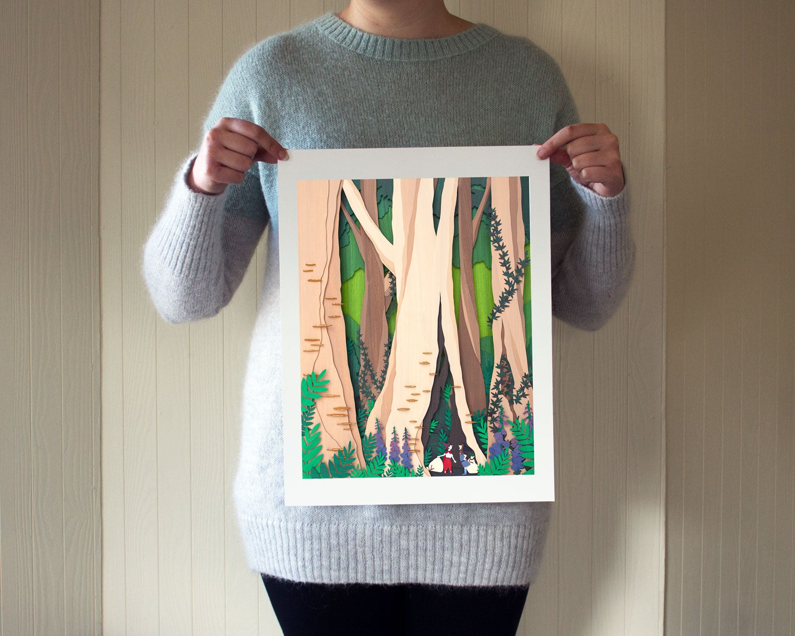 Archival print of cut paper illustration of cute whimsical forrest scene with two foragers featured at the bottom.