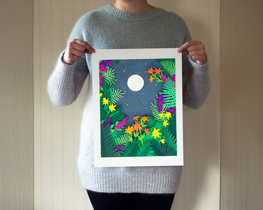 Person holding an archival print of cut paper illustration of night scene with full moon and stars rising framed by flowers and ferns.