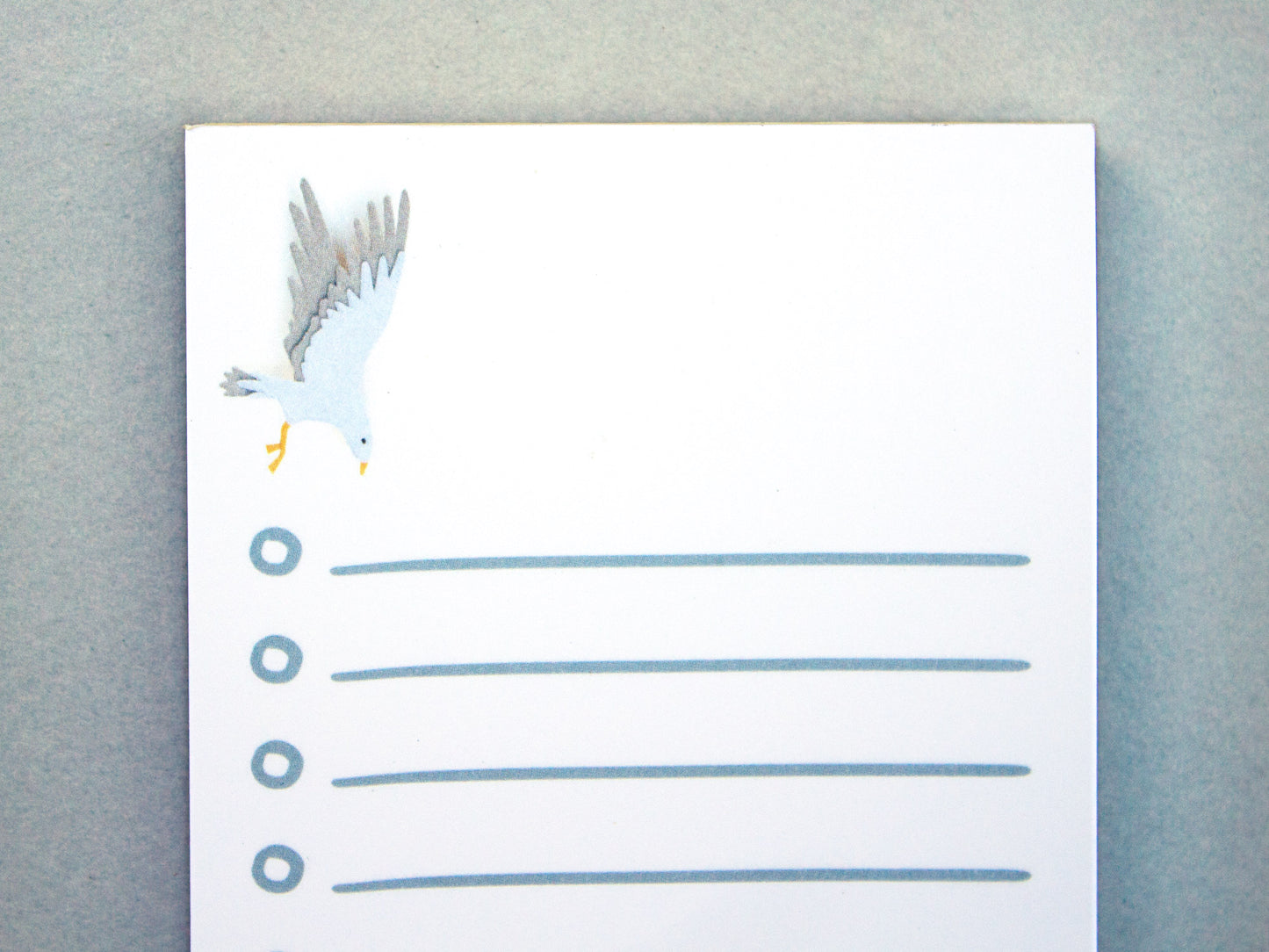 Cute notepad with cut paper illustration of blue sea serpent monster at bottom and sea gull at top.