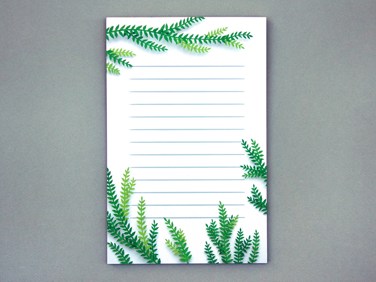 Notepad with cut paper illustration of tree branches at the top and bottom.
