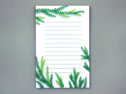 Notepad with cut paper illustration of tree branches at the top and bottom.