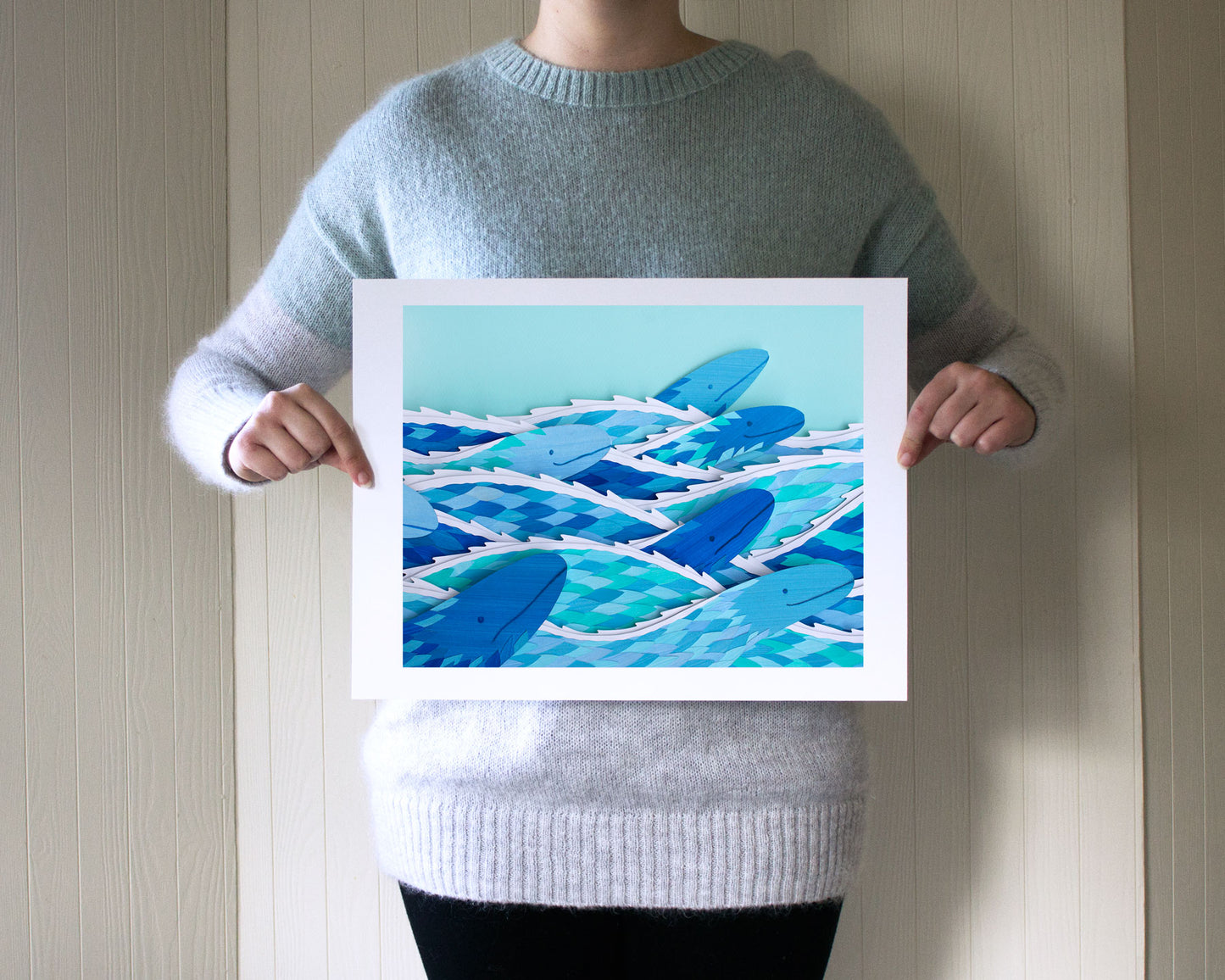 Archival print of cut paper illustration of several cute blue sea serpents swimming.