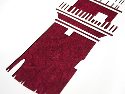 Framed simple deep red and white cut paper illustration of the Gay Head lighthouse in Aquinnah, on Martha's Vineyard.