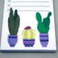 Cute notepad with cacti in purple pots at the bottom