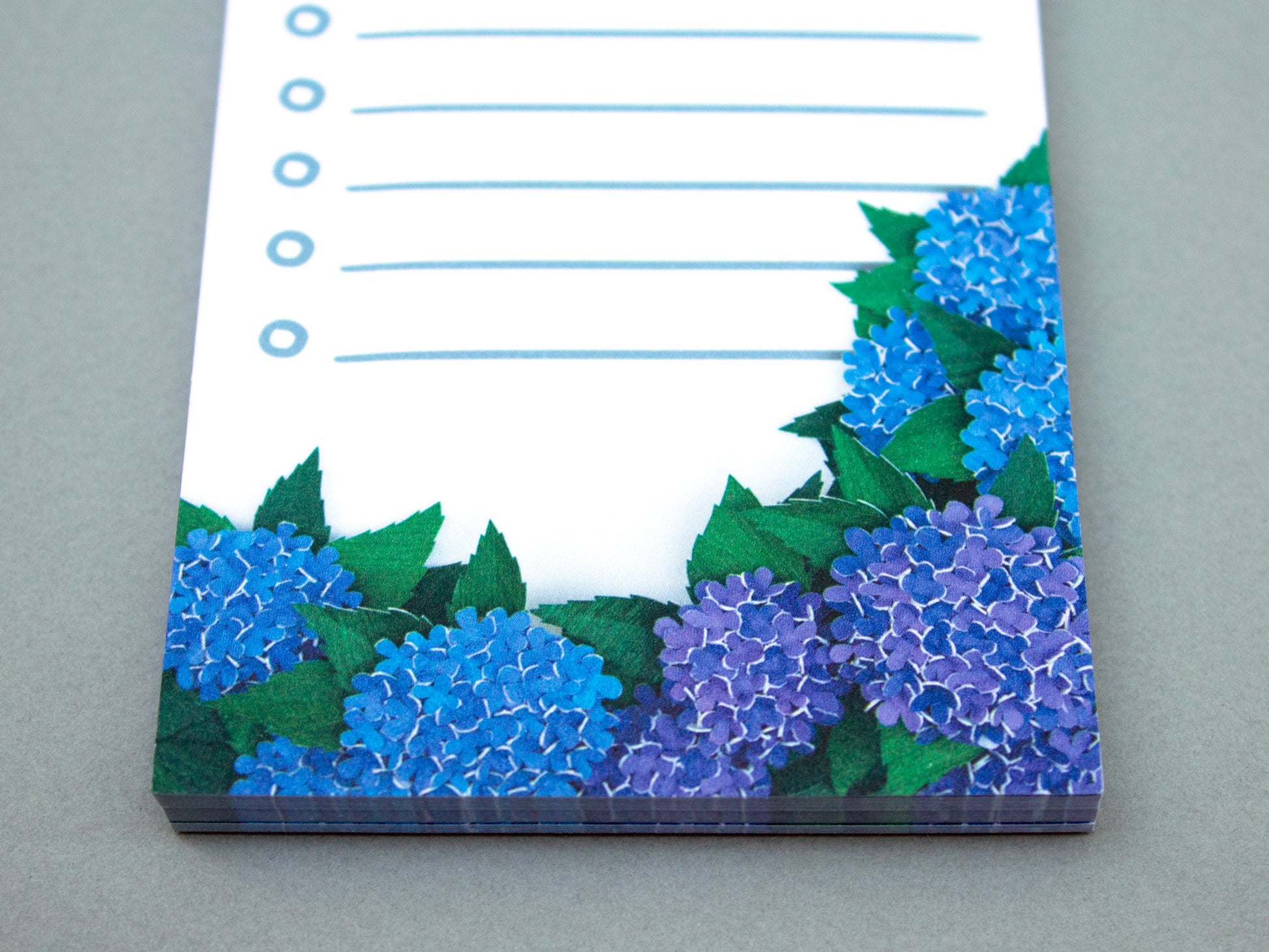 Cute notepad with cut paper illustration of blue hydrangea flowers.