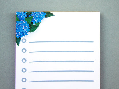 Cute notepad with cut paper illustration of blue hydrangea flowers.